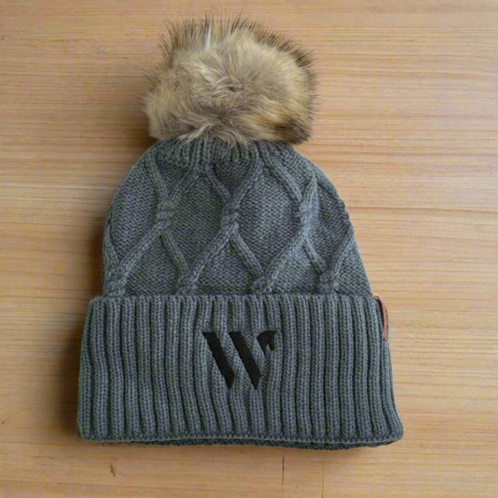 Gray knit beanie with a fur pom-pom on a light background