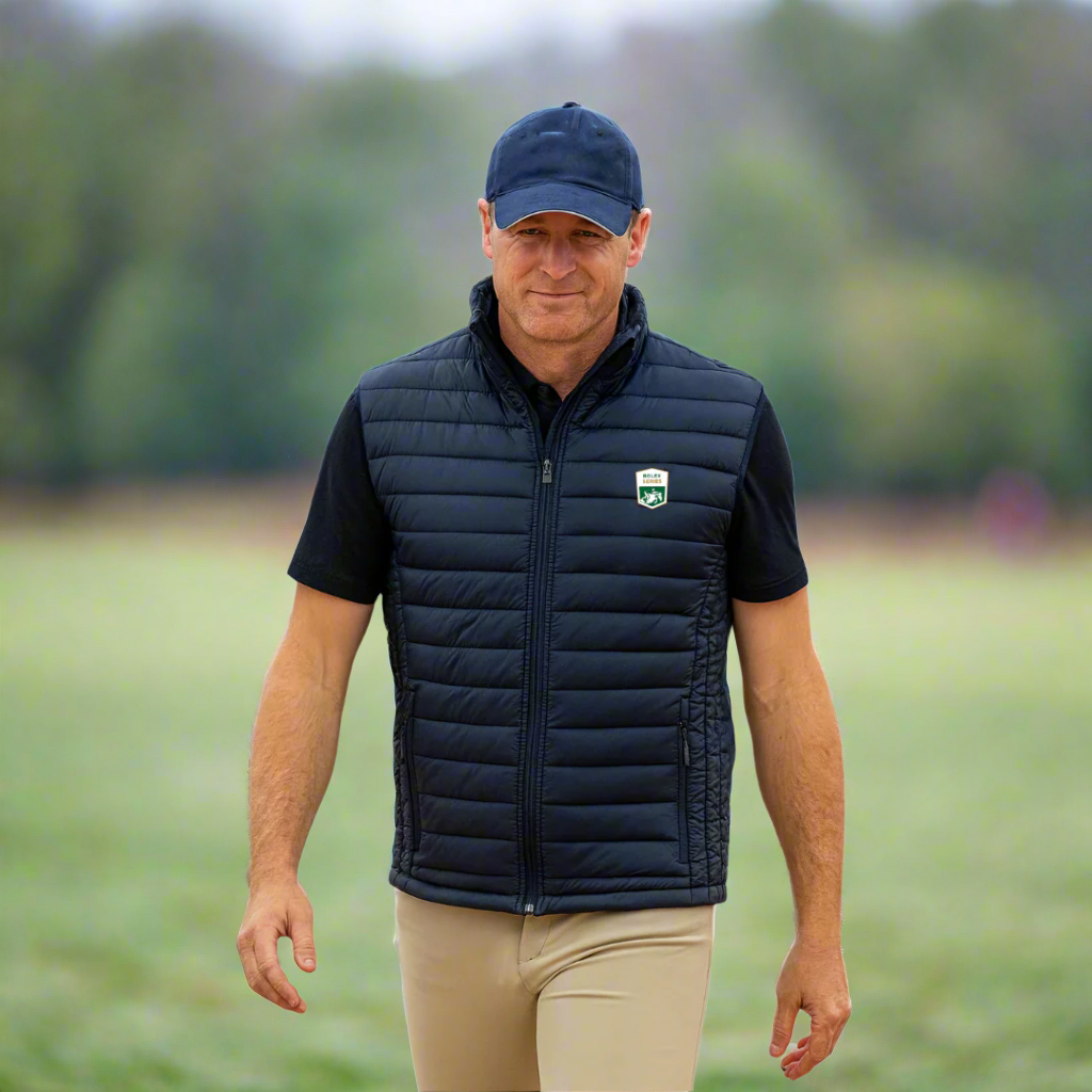 Man wearing a navy puffer vest with a logo outside