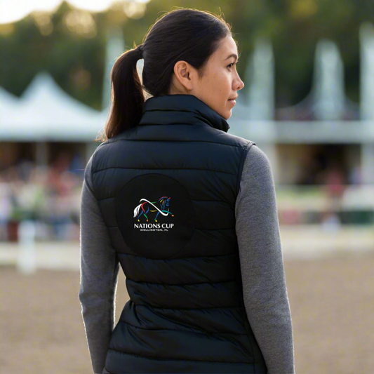 Person wearing a black puffer vest with dressage Nations Cup logo outside