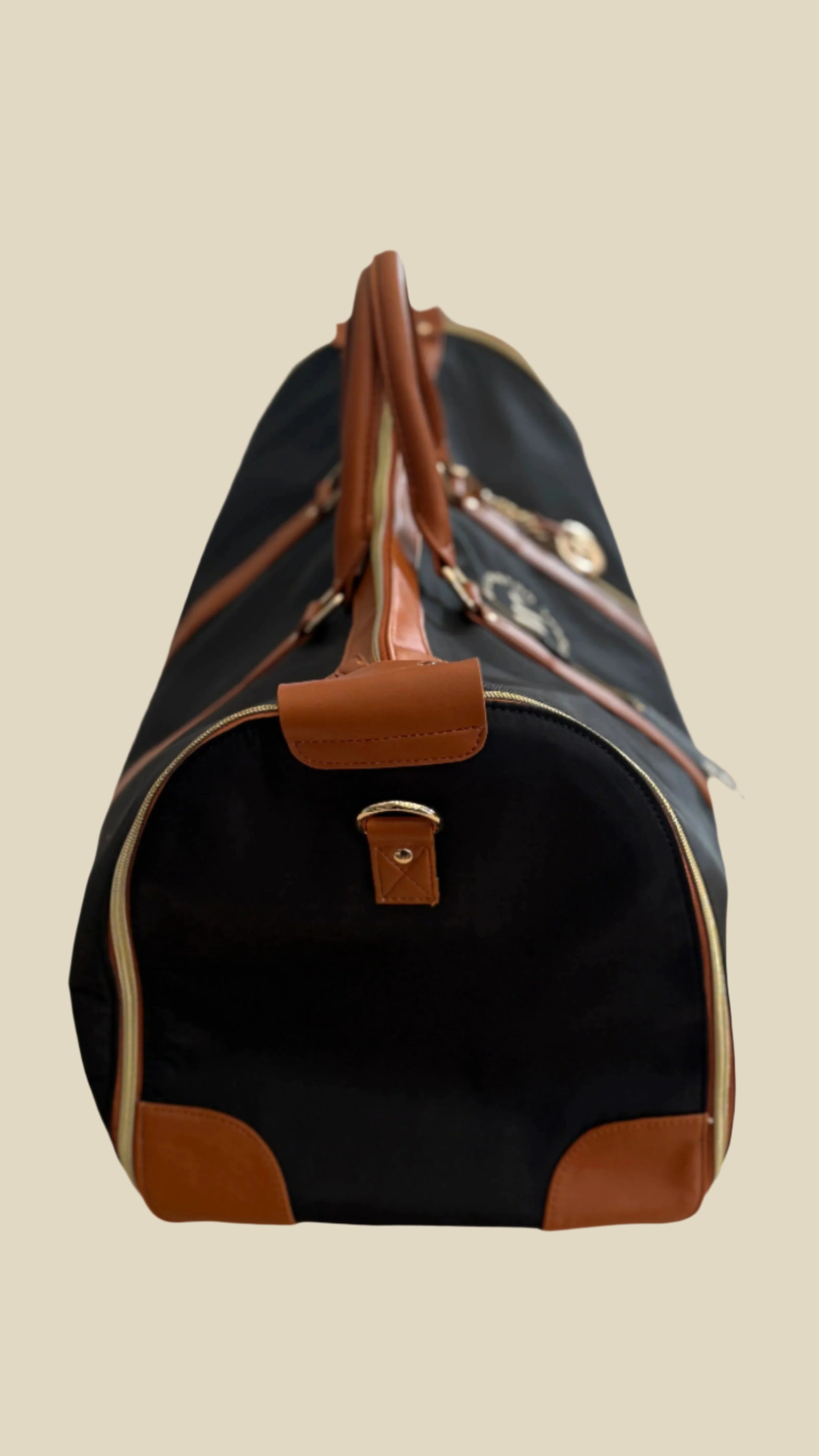 Black duffel bag with brown accents on a light-colored surface