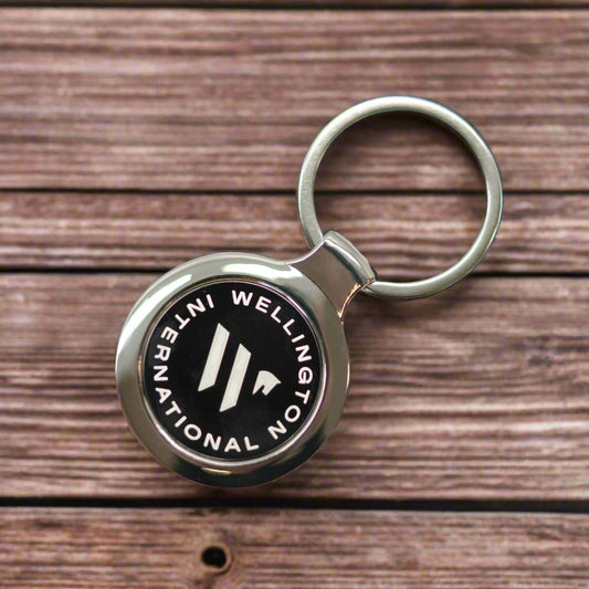 Keychain with Wellington International logo on a wooden desk background
