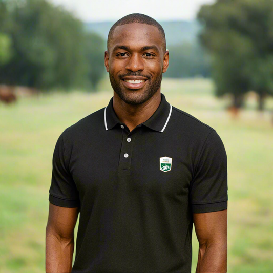 Man wearing a black polo shirt with a rolex series jumping logo on a farm