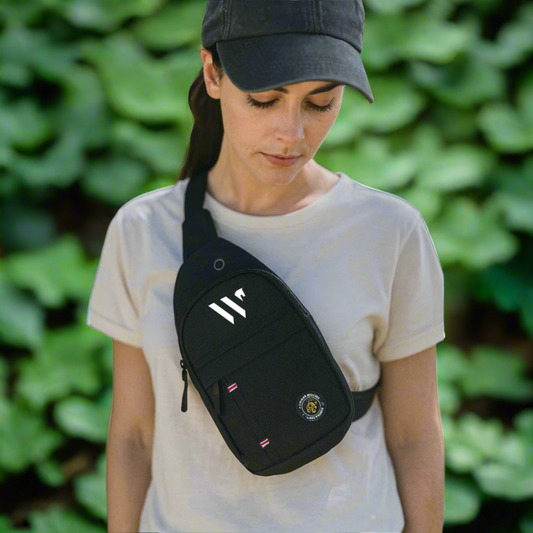Person wearing a black cross body bag over one shoulder on a green leaf background
