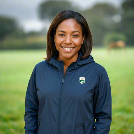 Woman wearing a blue rain coat with a rolex series equestrian logo outside