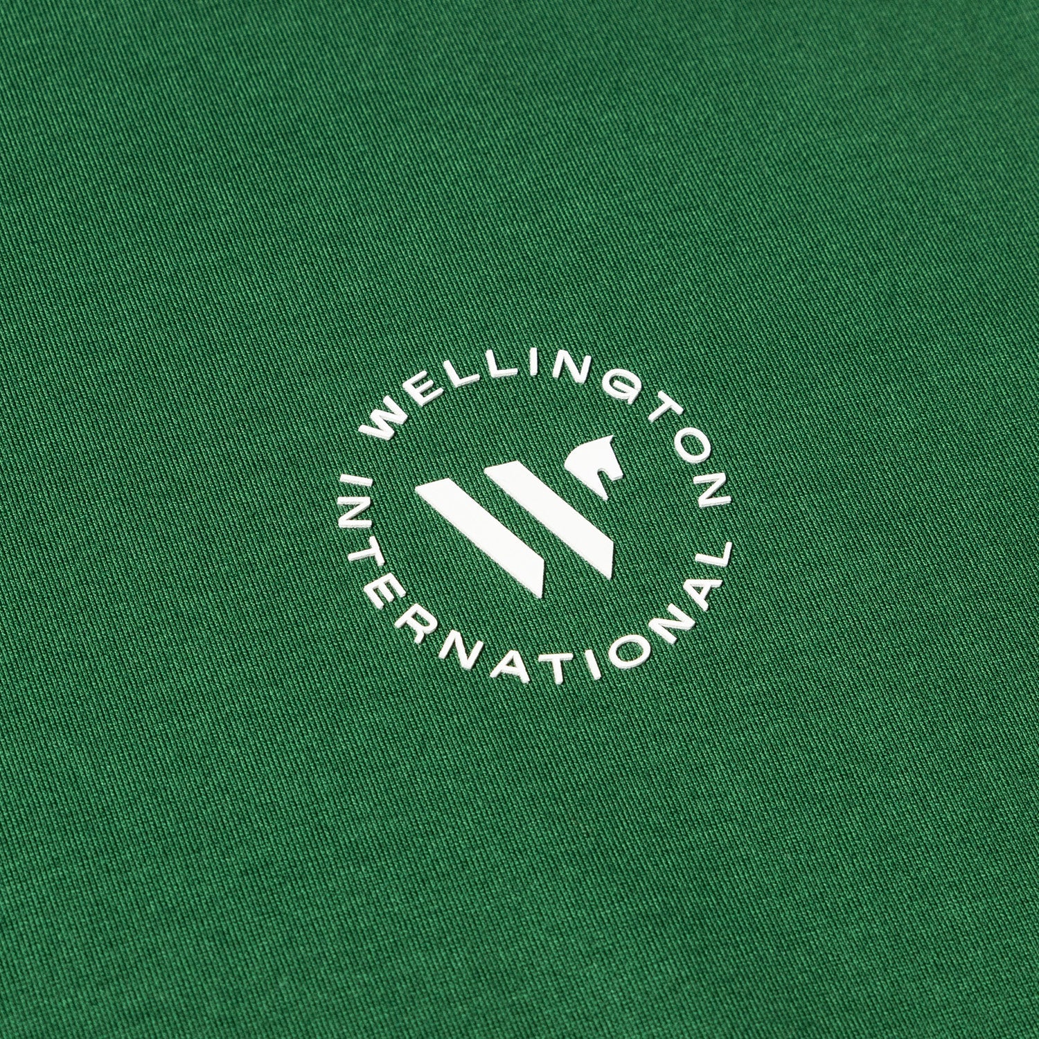 white Wellington International logo on green tshirt
